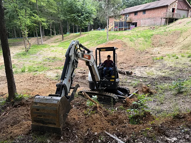 Mini excavator clearing a wooded slope