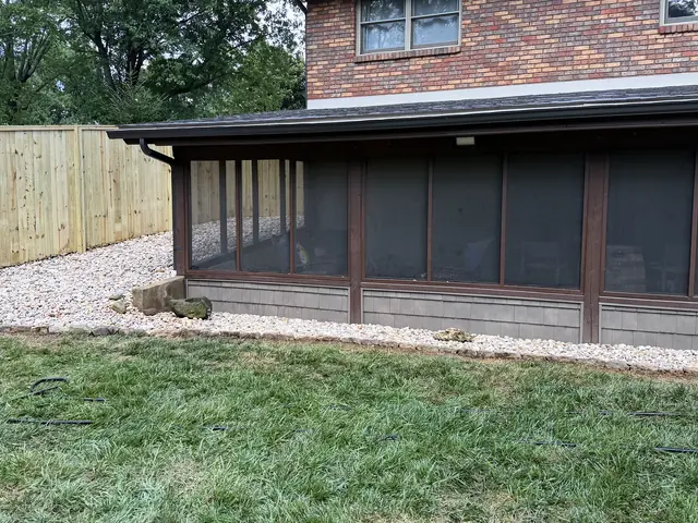 Decorative rock bed with block edging running along a fence line