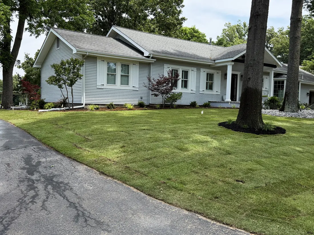 Freshly installed sod lawn with mulched planting beds and stone edging